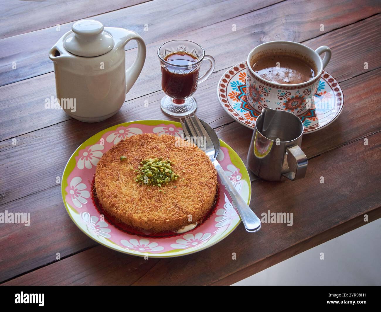 Kunafa o Kunefe è un dolce tradizionale mediorientale. Servito con caffè turco e caffè speziato su un tavolo di legno Foto Stock