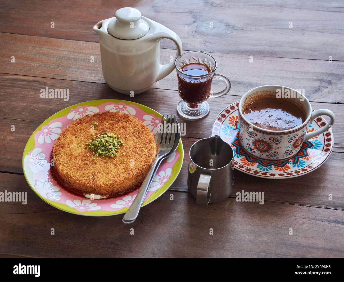 Kunafa o Kunefe è un dolce tradizionale mediorientale. Servito con caffè turco e caffè speziato su un tavolo di legno Foto Stock