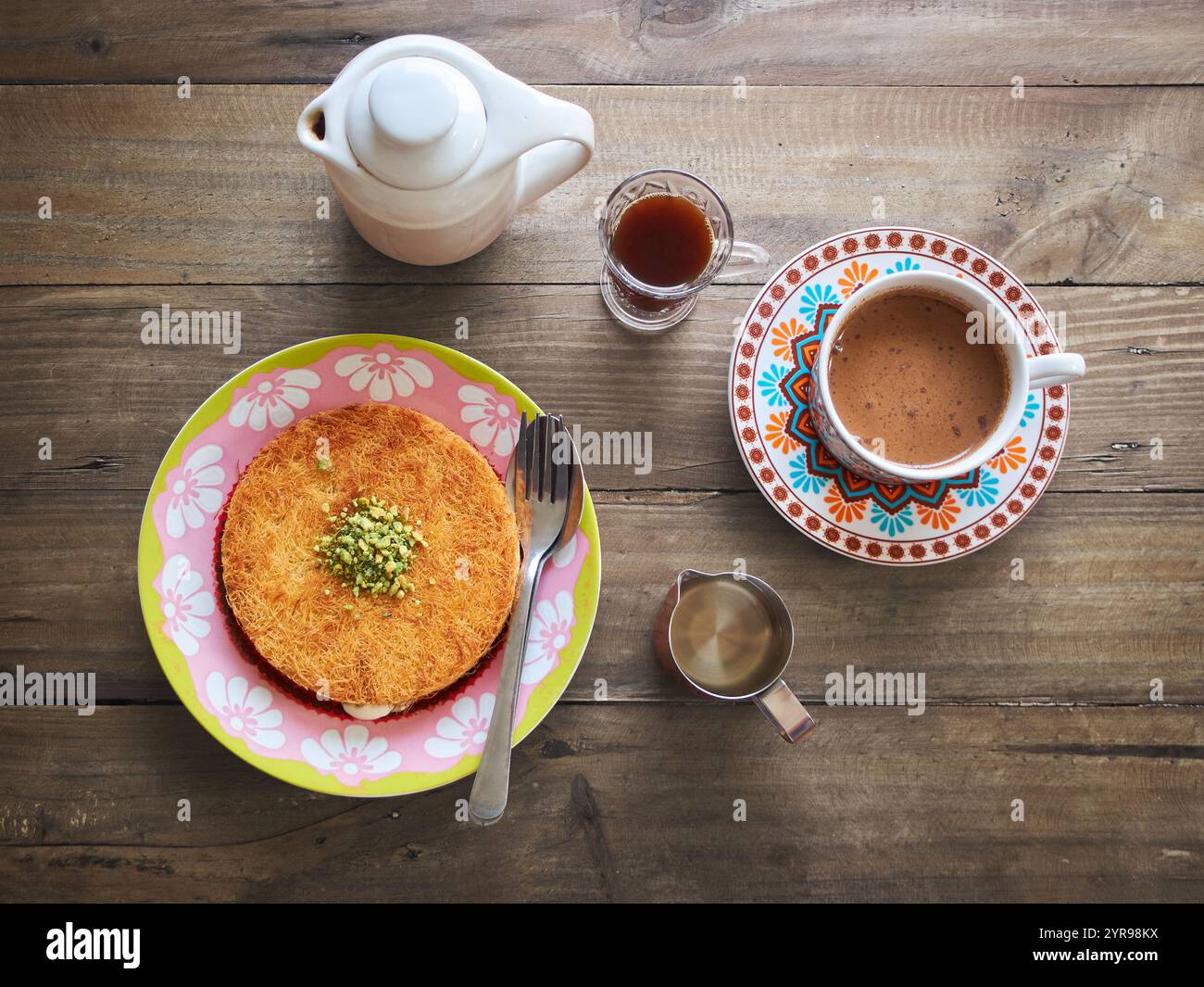 Kunafa o Kunefe è un dolce tradizionale mediorientale. Servito con caffè turco e caffè speziato su un tavolo di legno Foto Stock