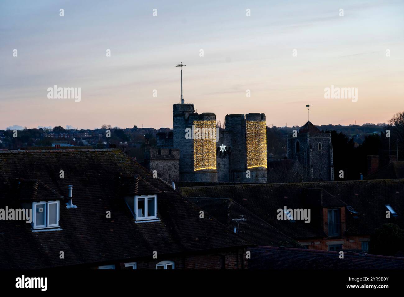 Luci di Natale sulla Westgate Tower. Le mura della città di Canterbury nel XXI secolo sono un misto di sopravvissuti dai molteplici periodi di costruzione, dai romani al XX secolo, ma la maggior parte delle mura visibili sono di origine medievale. Delle 24 torri medievali originali lungo le mura, 17 rimangono intatte, e un ingresso alla città, il Westgate, sopravvive. Canterbury è una città e patrimonio dell'umanità dell'UNESCO, nella contea del Kent, in Inghilterra; è stato un borough di contea fino al 1974. Si trova sul fiume Stour. Foto Stock