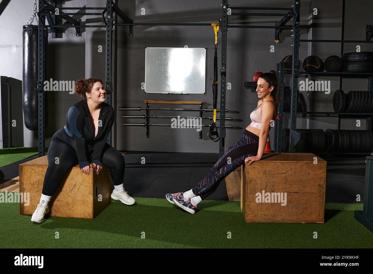 Due amici si godono una pausa mentre si allenano in palestra, condividendo Risate e motivazione. Foto Stock