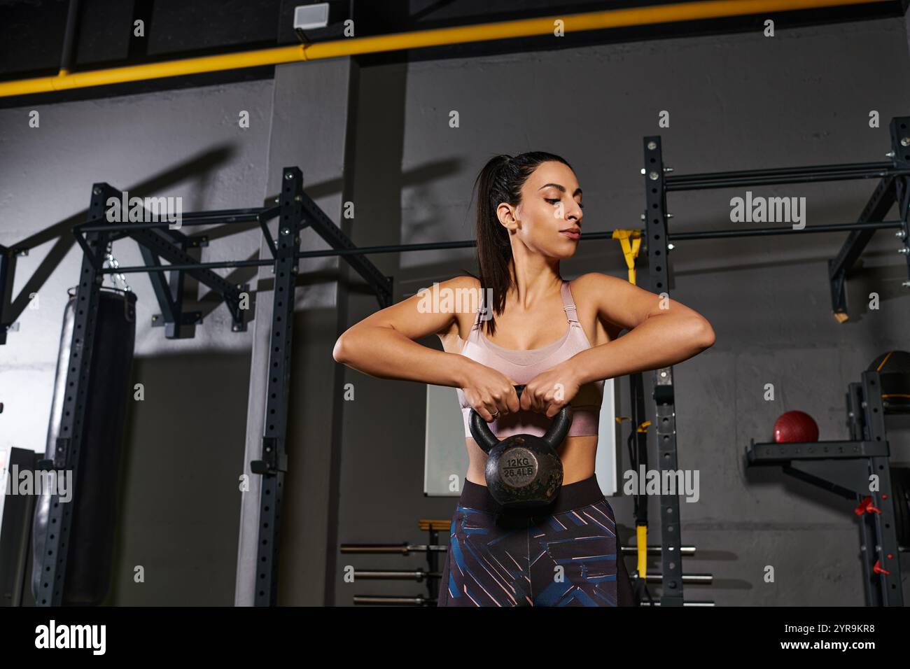 la donna fa allenamenti con kettlebell in una palestra urbana, aumentando la forza e il fitness. Foto Stock