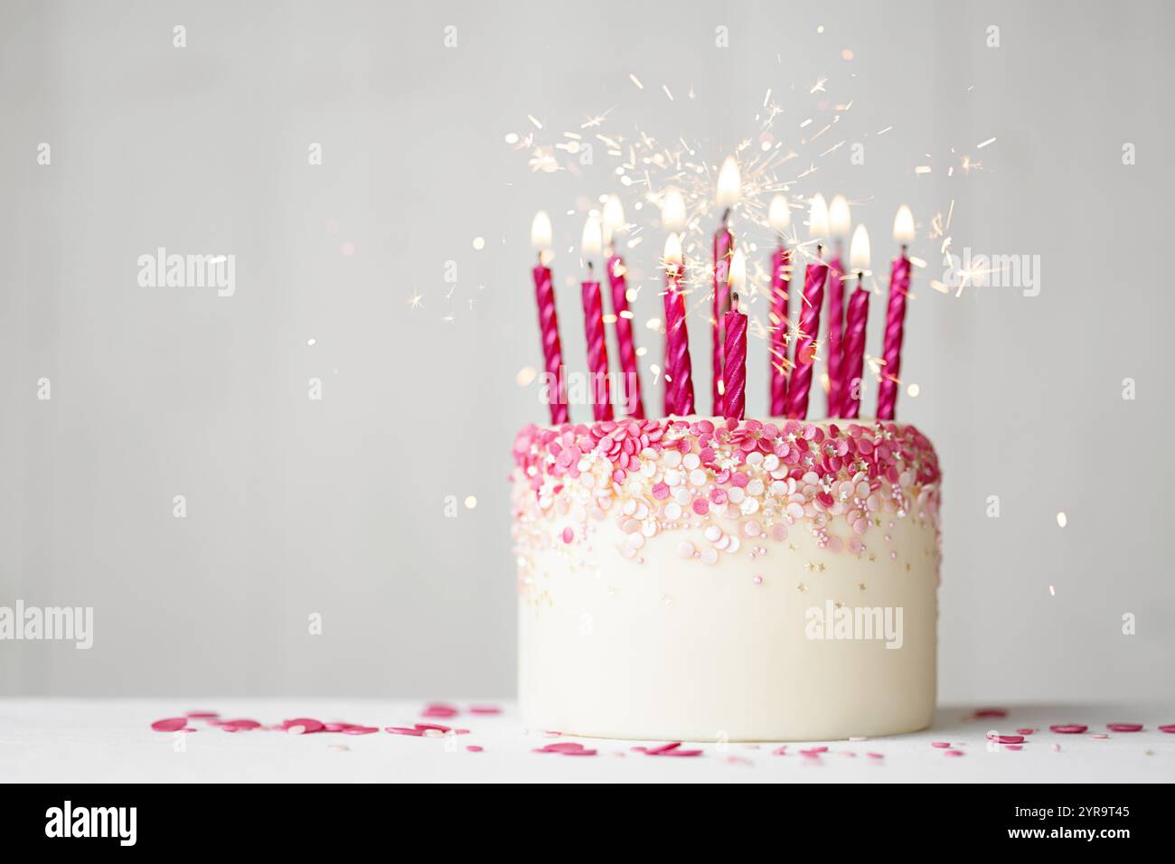 Torta di compleanno rosa con spruzzette rosa, candele di compleanno rosa e scintillanti Foto Stock