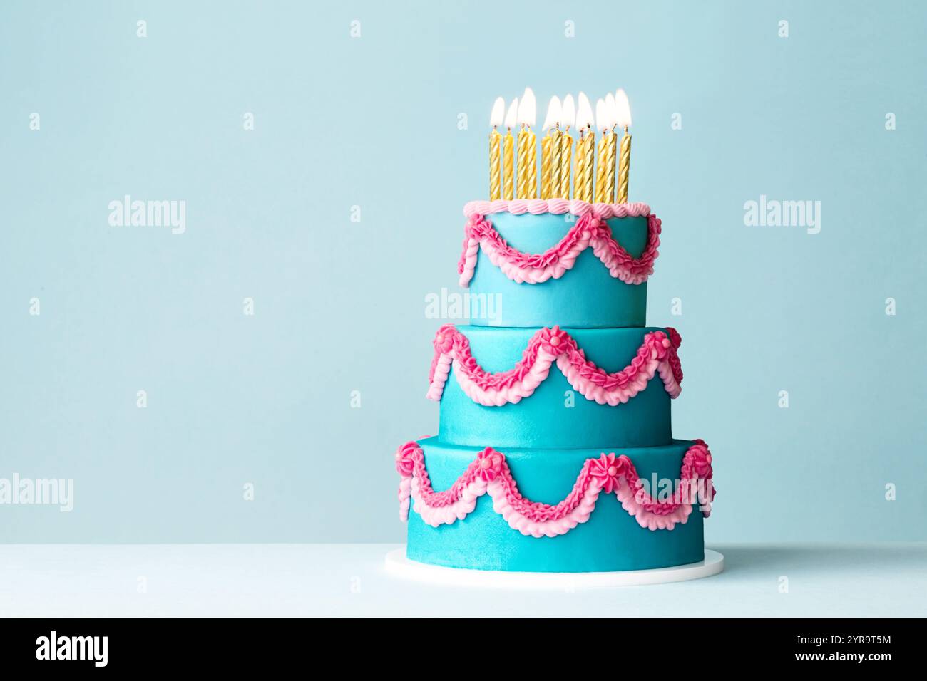 Torta di compleanno a più piani con fronzoli color crema di burro e candele d'oro Foto Stock