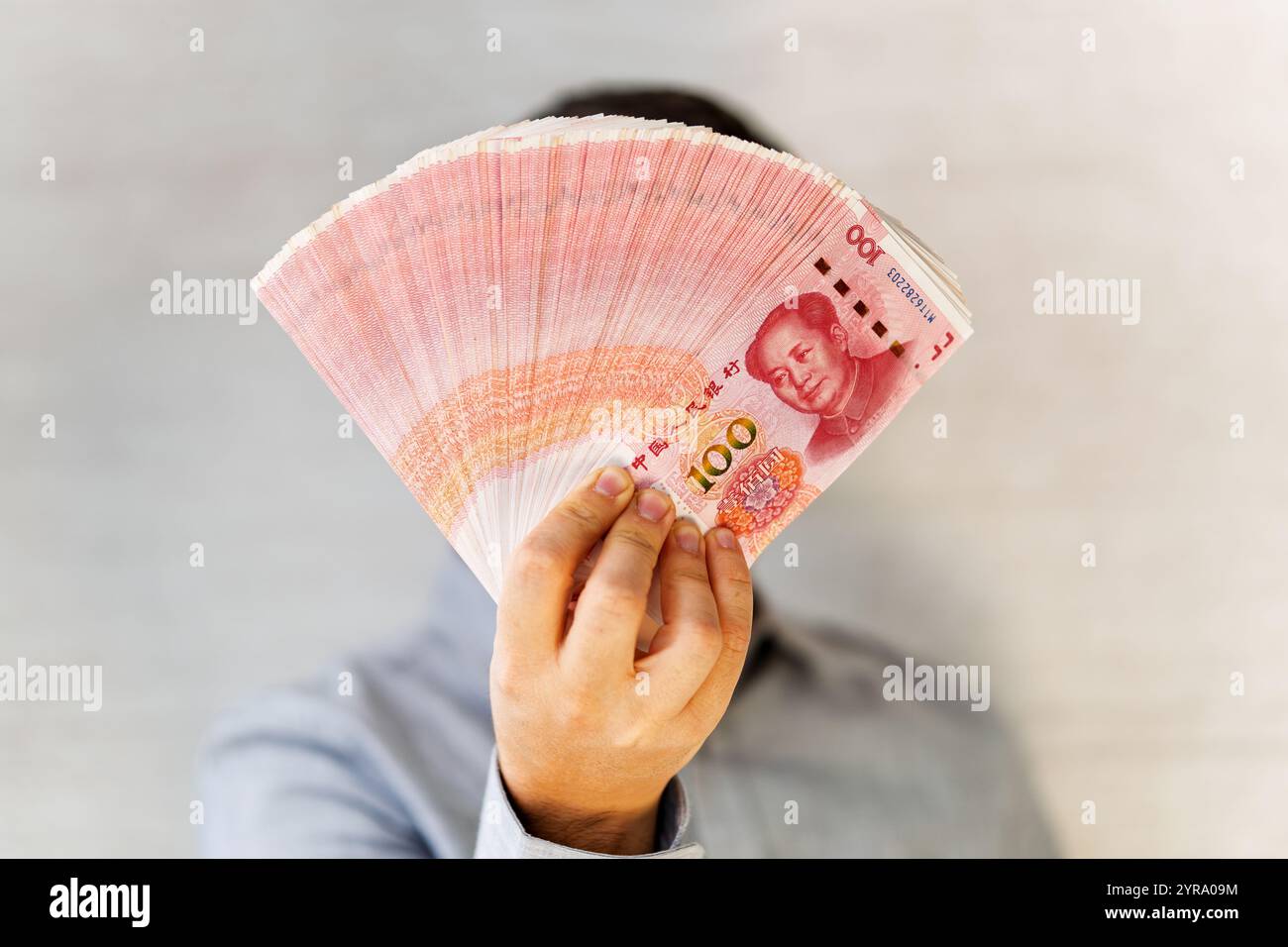 Yuan cinese nelle mani. Uomo d'affari in camicia blu con un Chineseyuan. un fan dei soldi Foto Stock