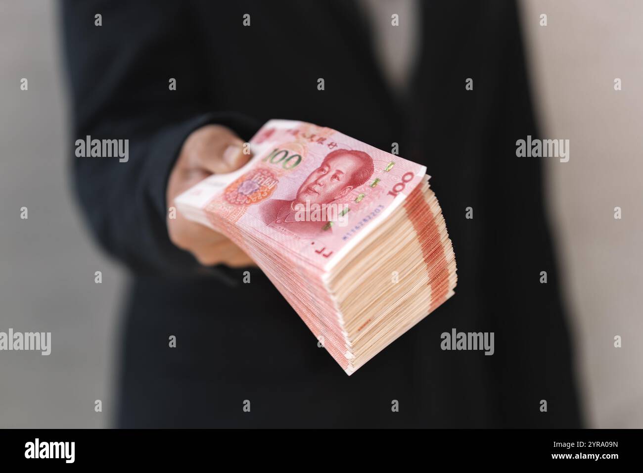 Le mani di una persona che ti propone dei soldi... primo piano. Un uomo tiene in mano lo yuan cinese. Il capo paga lo stipendio. Il concetto di corruzione e corr Foto Stock