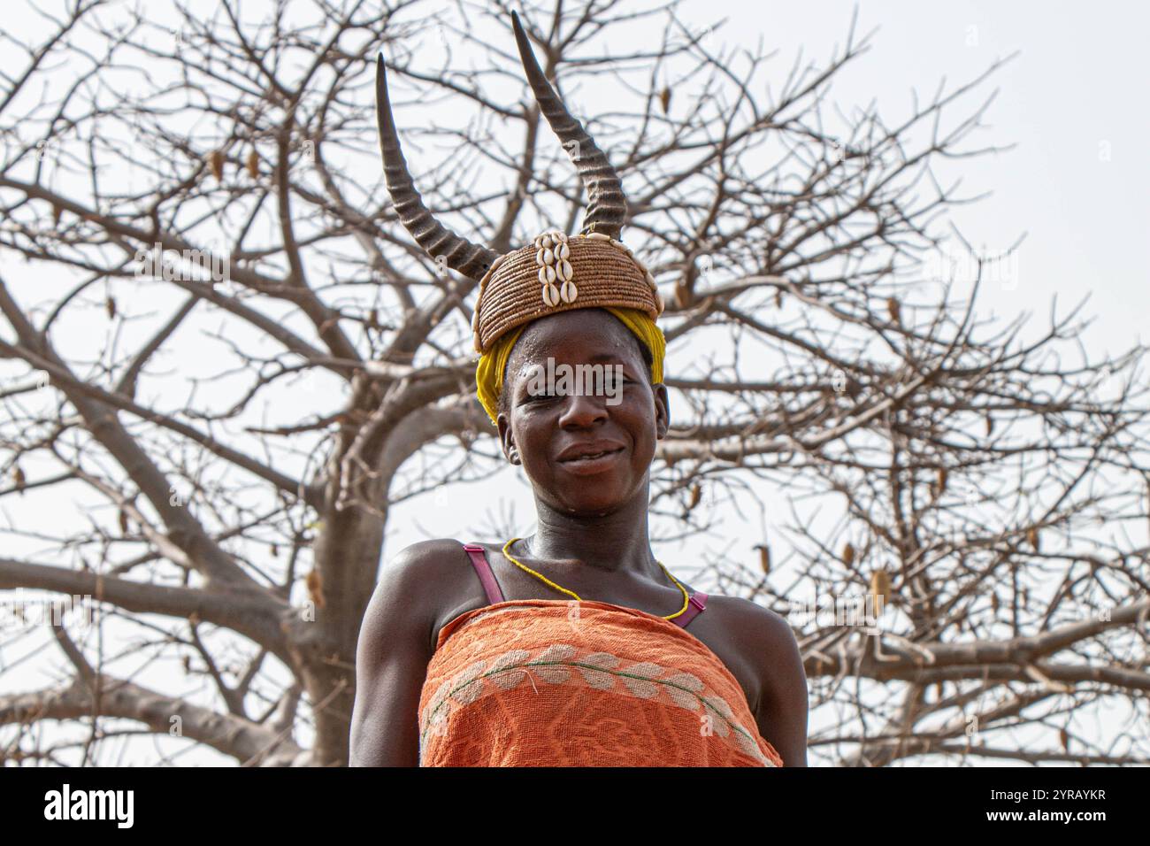Donna in costume tradizionale con cappello cornuto sorridente in un villaggio rurale in Togo Foto Stock