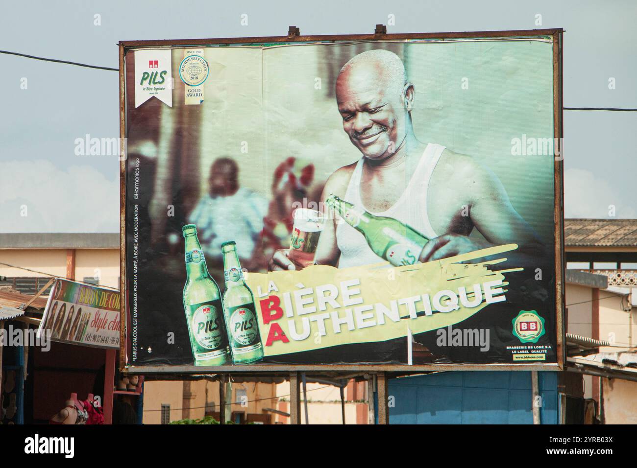 Billboard Advertising Local Beer in Togo con un uomo sorridente che versa un bicchiere Foto Stock