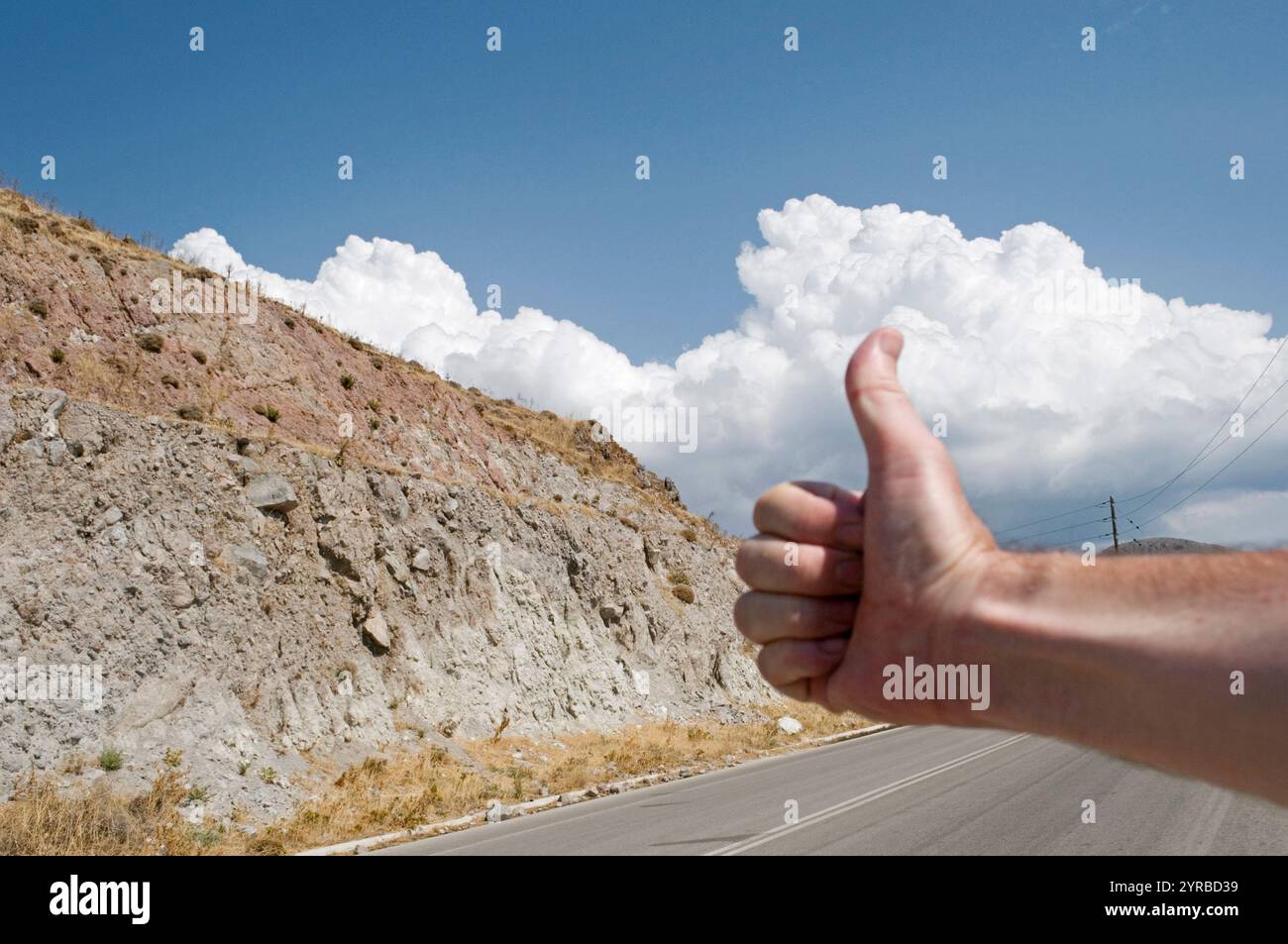 Persona irriconoscibile con gesti del pollice e aggancio sul bordo della strada. Parole chiave Foto Stock