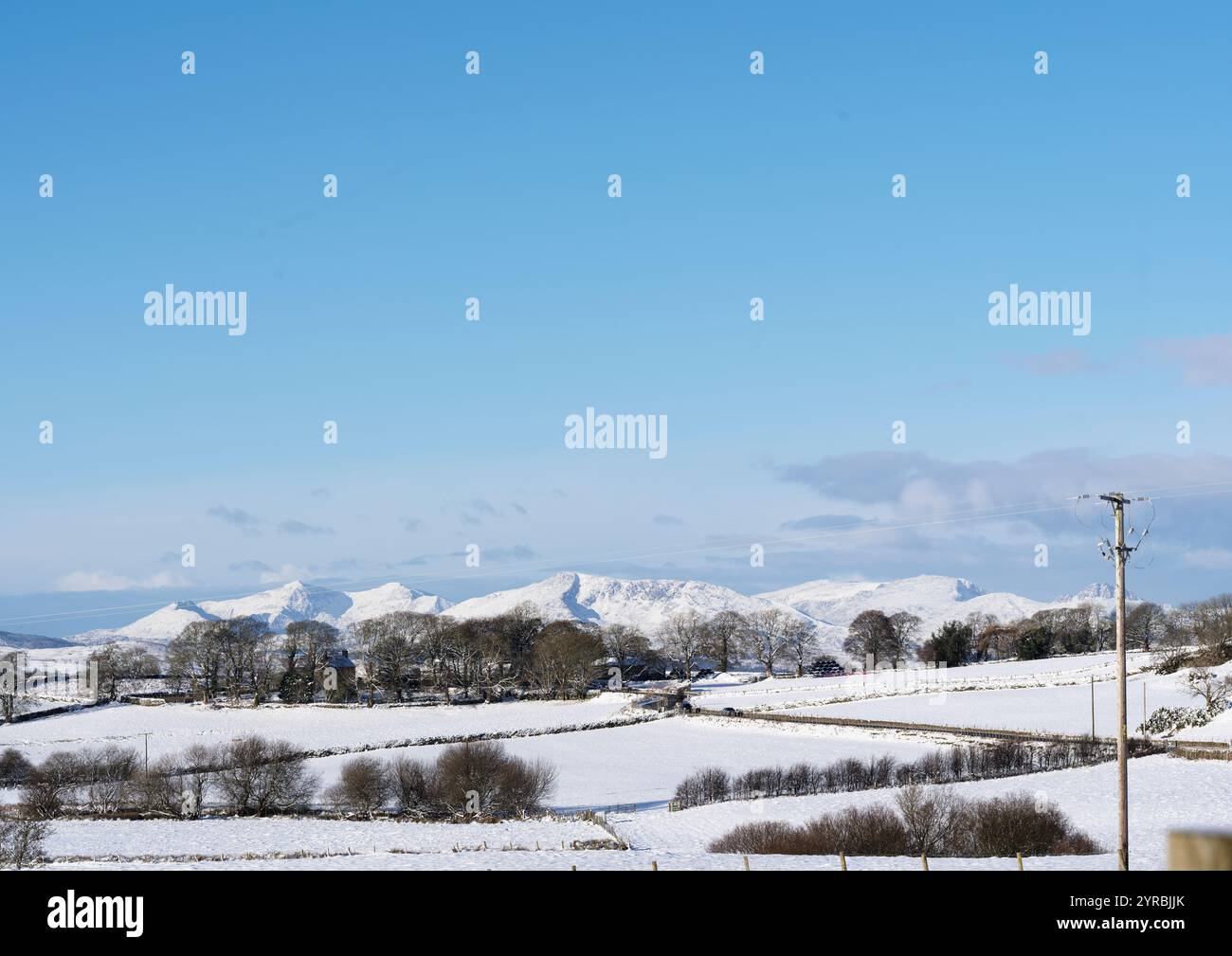 Montagne di Snowdonia (Eryri), incluso il Monte Snowdon (Yr Wyddfa) sulla sinistra, viste dai campi carichi di neve vicino al villaggio di Glasfryn, Galles. Foto Stock