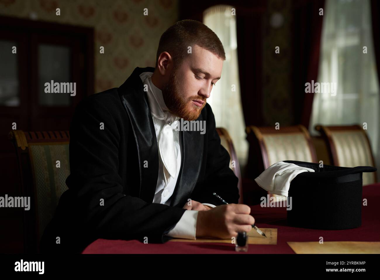 Vista laterale ritratto di un giovane gentiluomo che indossa un cappotto in velluto e una lettera con penna a inchiostro seduta in un interno classico, spazio per le copie Foto Stock