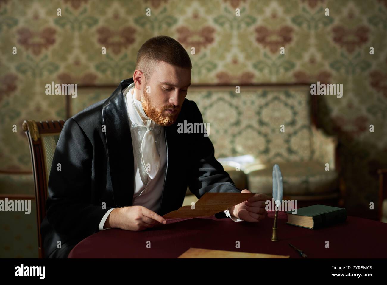 Ritratto in vita di un giovane gentiluomo in un classico abbigliamento formale seduto a tavola tenendo in mano una lettera, copia spazio Foto Stock