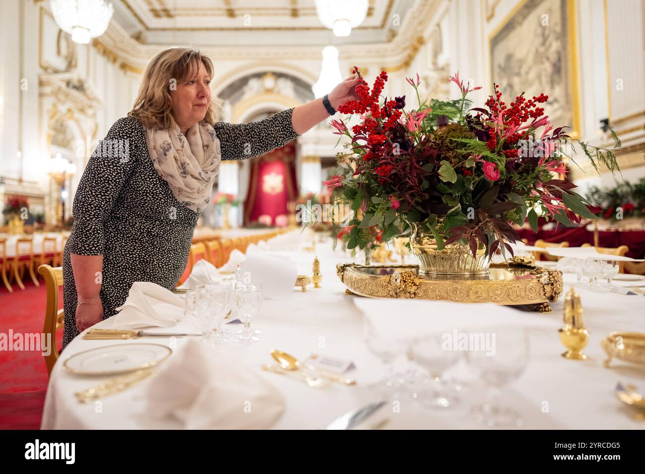 I ritocchi finali sono applicati ai fiori stagionali, da un fiorista reale, ai tavoli della sala da ballo di Buckingham Palace, Londra prima del banchetto di Stato per l'emiro del Qatar Sheikh Tamim bin Hamad al Thani, durante la sua visita di stato nel Regno Unito. Data foto: Martedì 3 dicembre 2024. Foto Stock