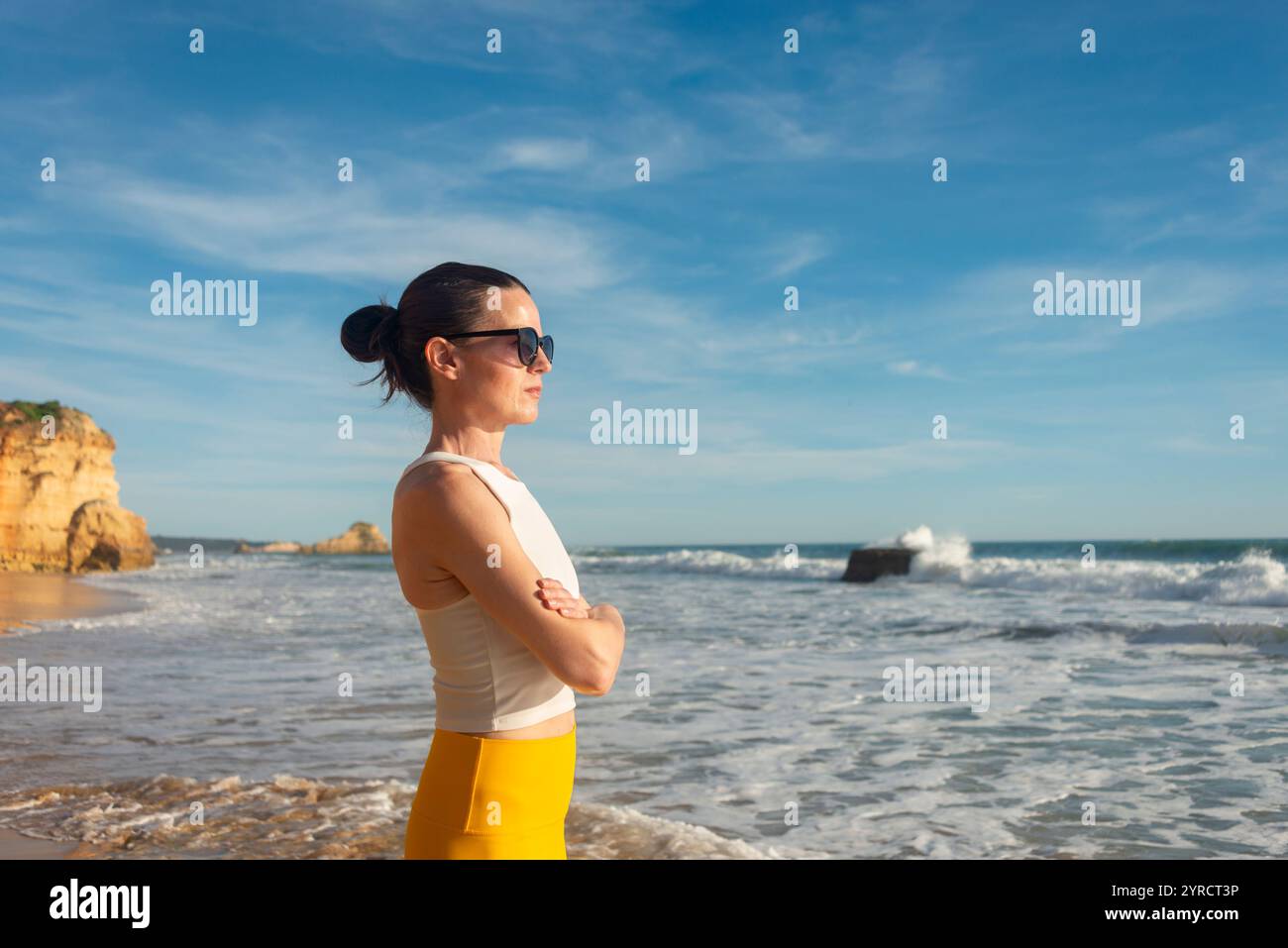 Donna sportiva in piedi che guarda al mare, riposante dopo l'esercizio fisico sulla spiaggia Foto Stock
