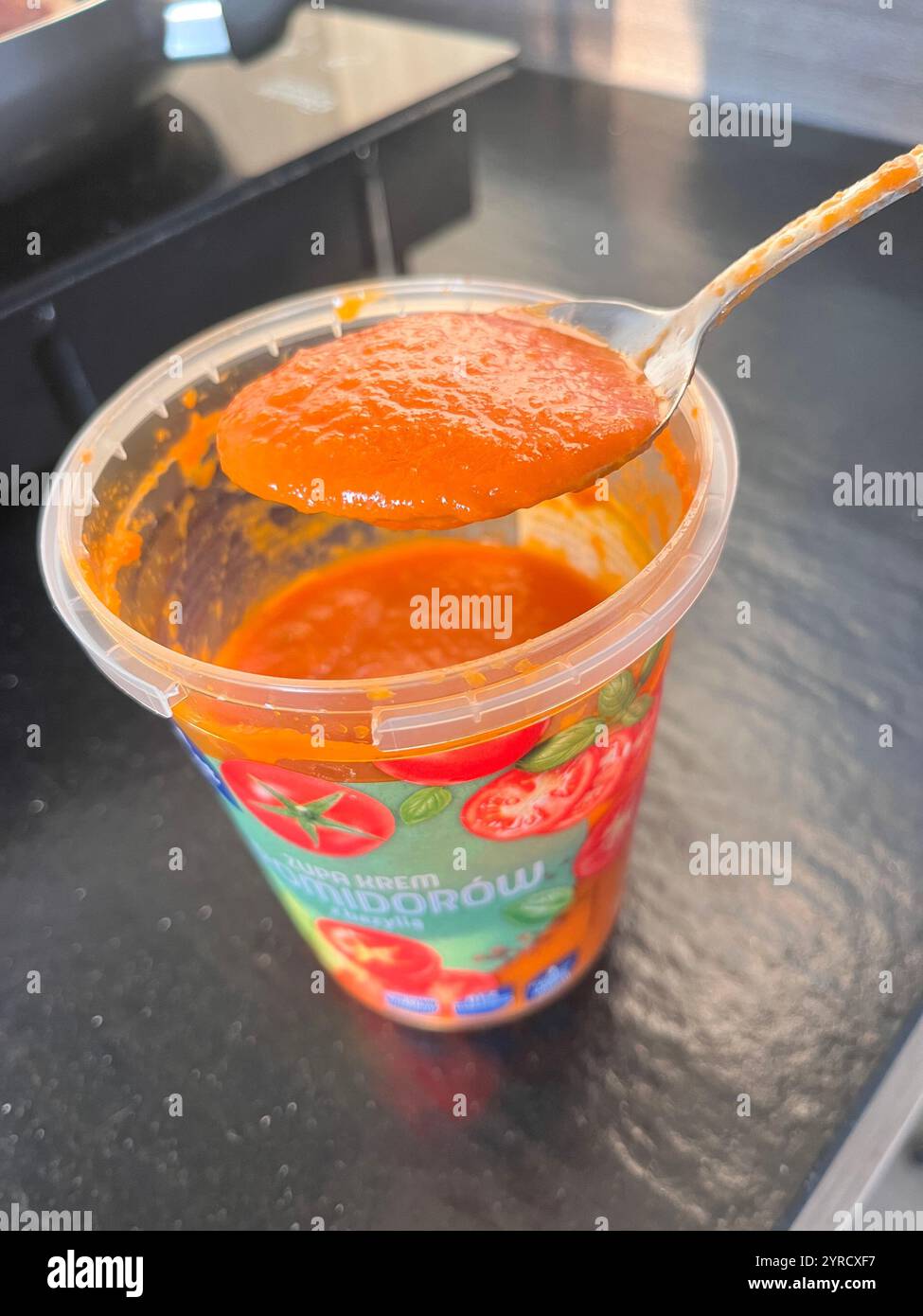 Cucchiaio di zuppa di pomodoro proveniente da un contenitore in plastica di marca polacca - Immagine stock catturata con smartphone