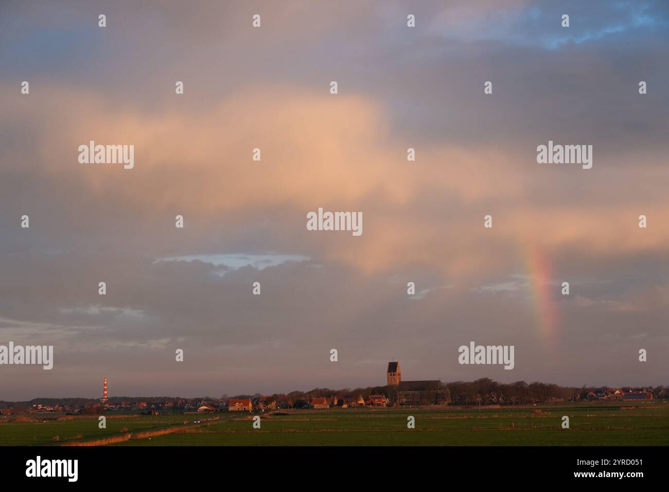 Rainbow, villaggio, torre della chiesa e faro la mattina presto, il villaggio Hollum sull'isola olandese di Ameland Foto Stock