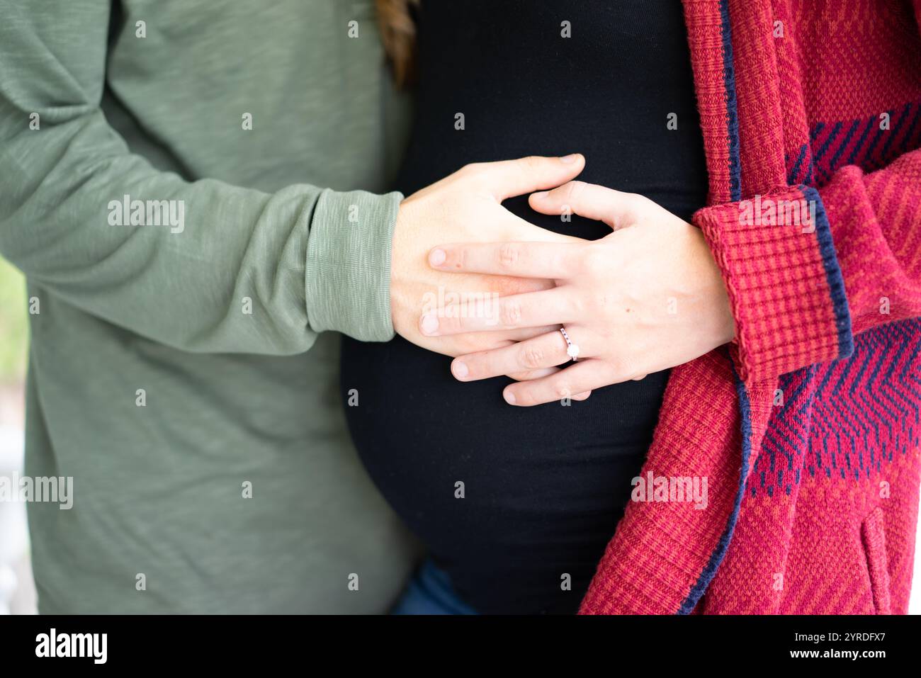 Mani amorevoli sulla pancia incinta in un accogliente ambiente autunnale Foto Stock