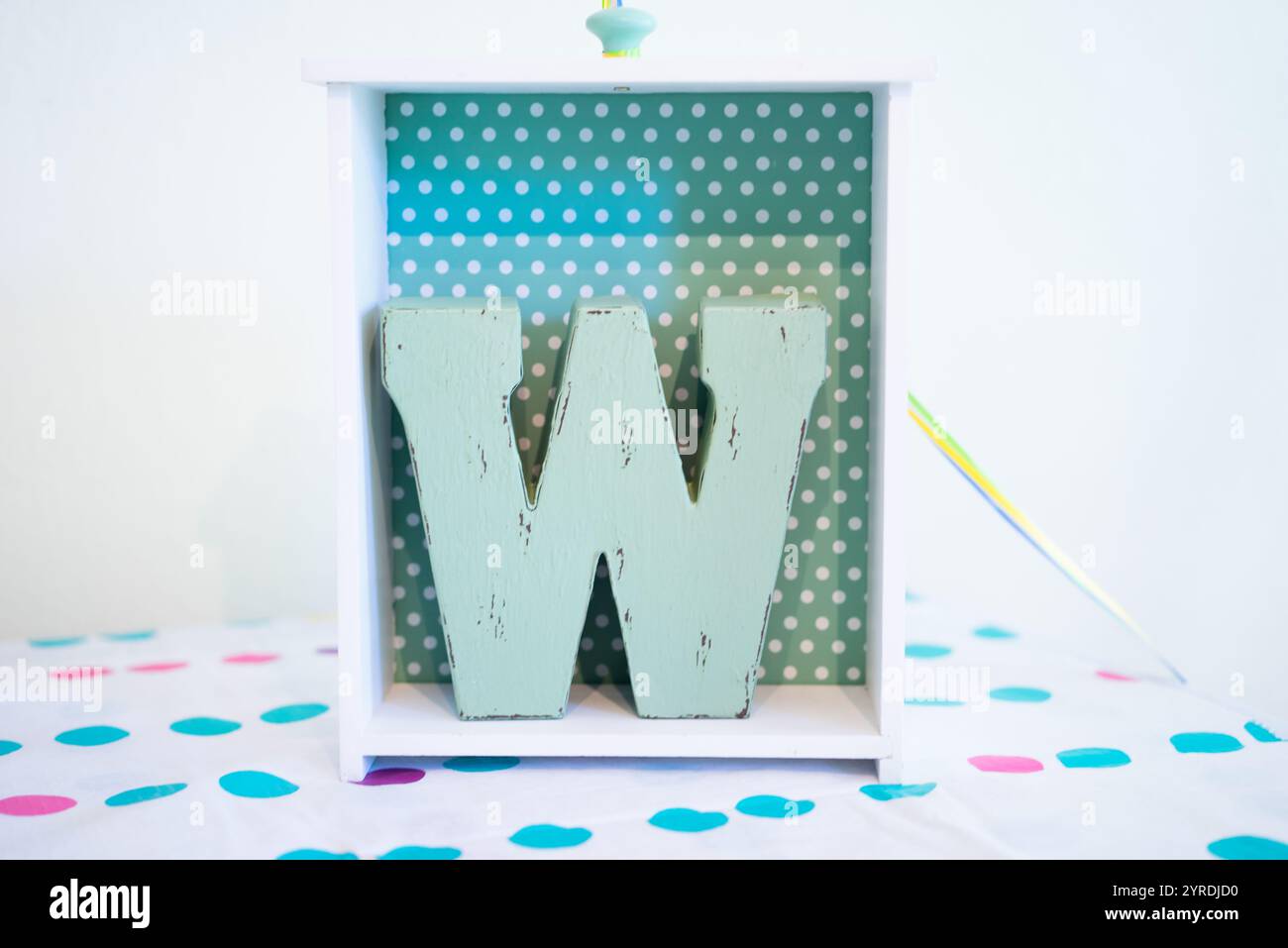 Lettera "W" in legno vintage in Polka Dot Box decorativa su sfondo a motivi geometrici Foto Stock