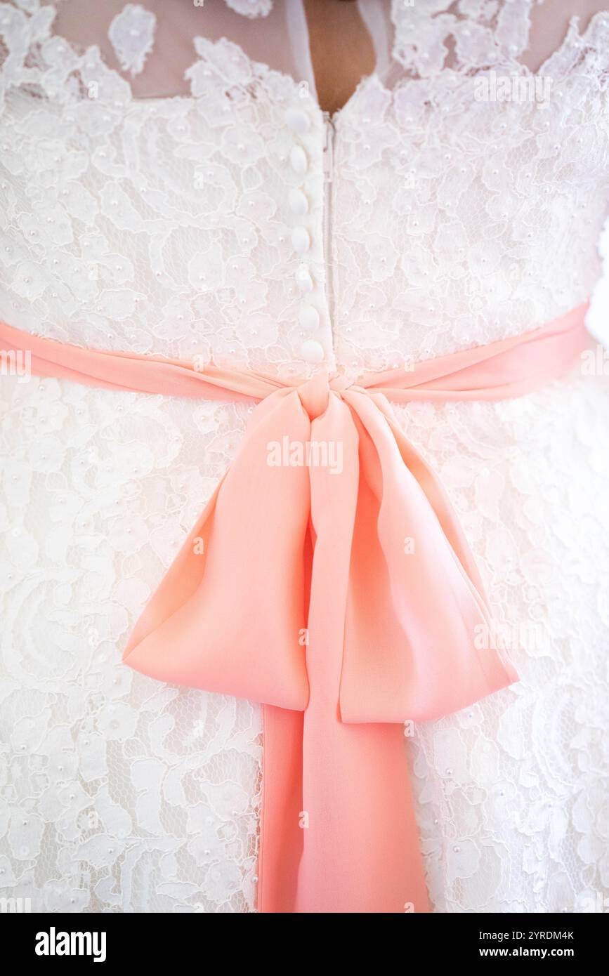 Elegante abito da sposa in pizzo bianco con un morbido fiocco rosa Foto Stock