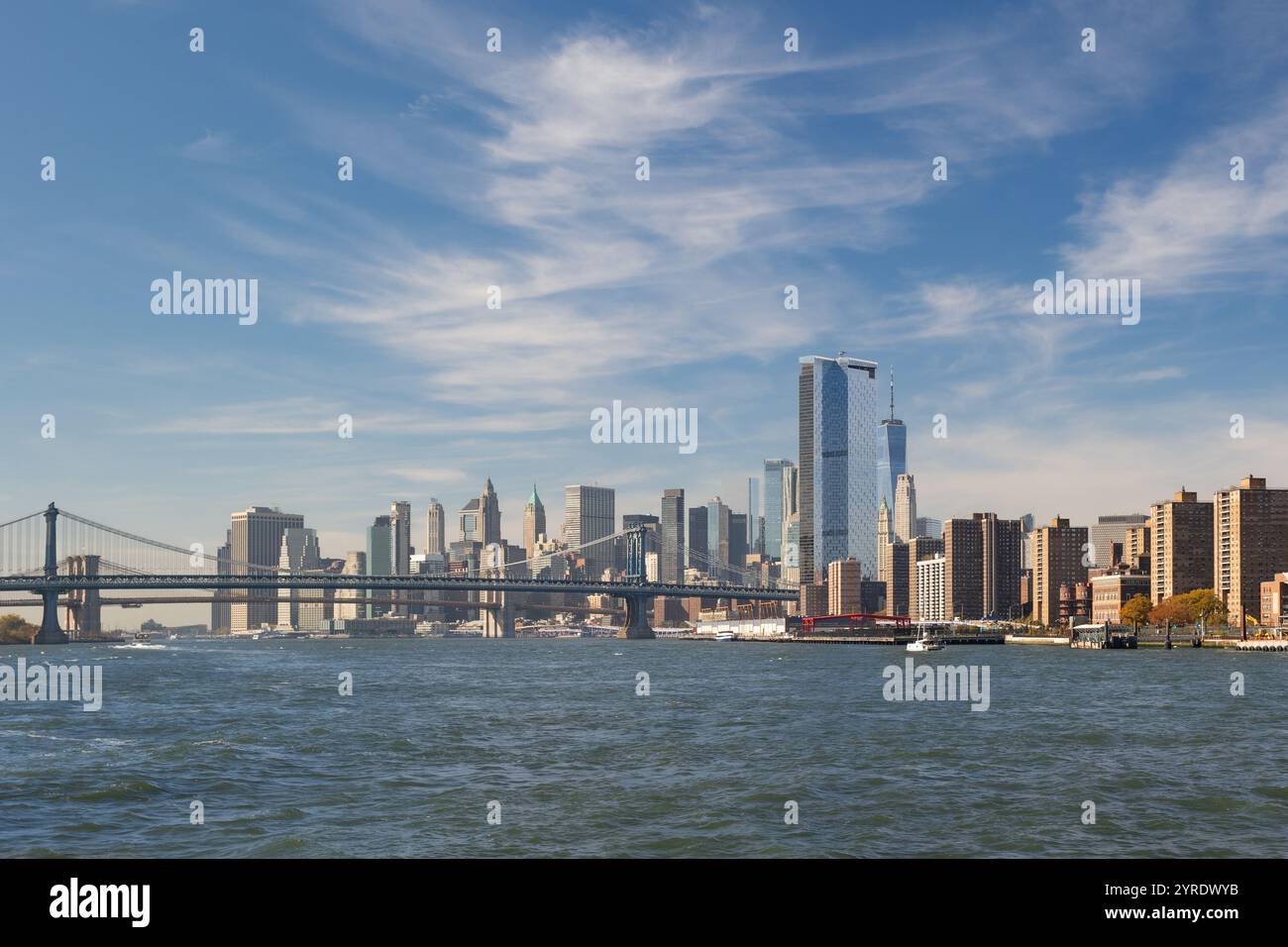 Una vista accattivante di New York City mostra il suo vivace skyline e un elegante ponte sotto un cielo limpido. Foto Stock