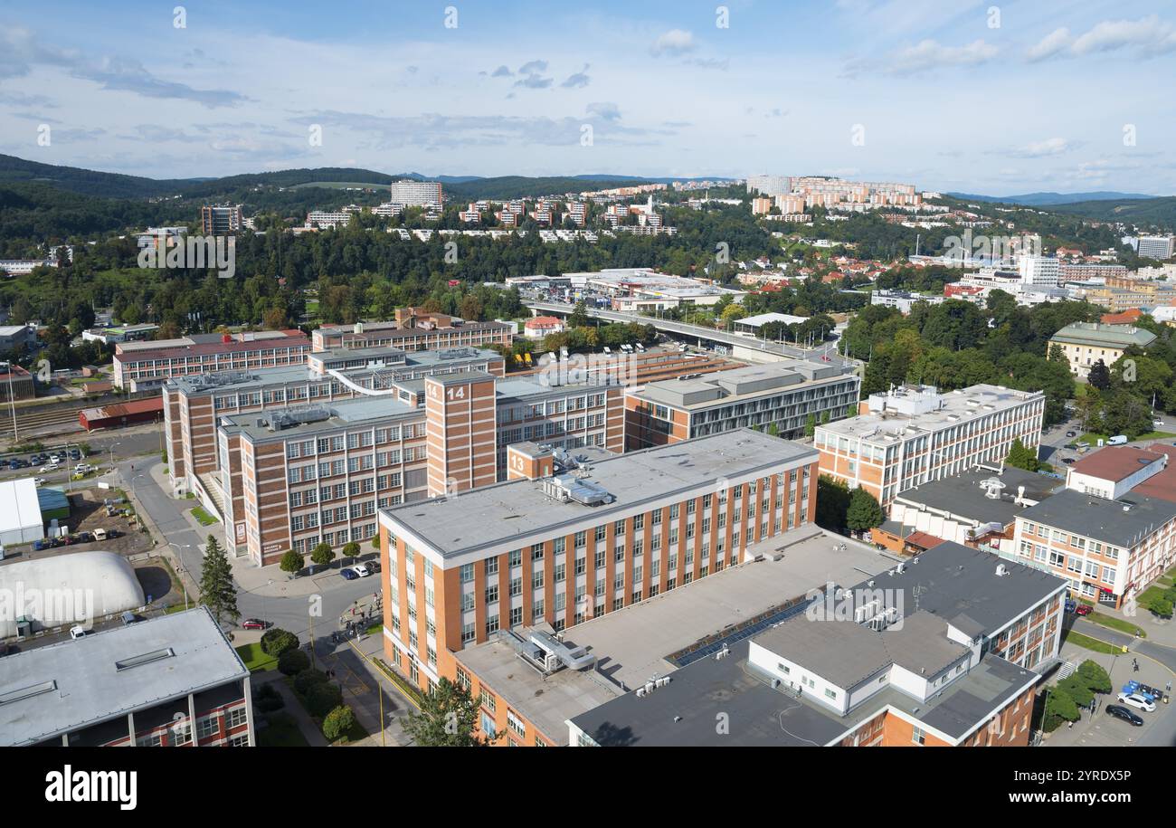 Panoramica di una città con edifici e alberi verdi, circondata da un paesaggio collinare, vista da Batuv Mrakodrap, grattacielo Batas sulla città, Zlin, Foto Stock