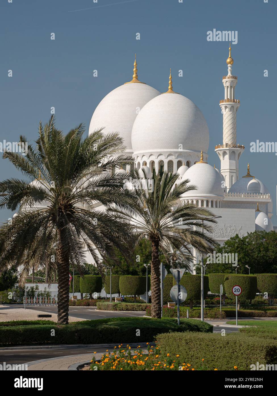 Grande Moschea dello Sceicco Zayed ad Abu Dhabi, Emirati Arabi Uniti, con le sue iconiche cupole bianche, minareti dorati e lussureggianti palme sotto un cielo azzurro Foto Stock