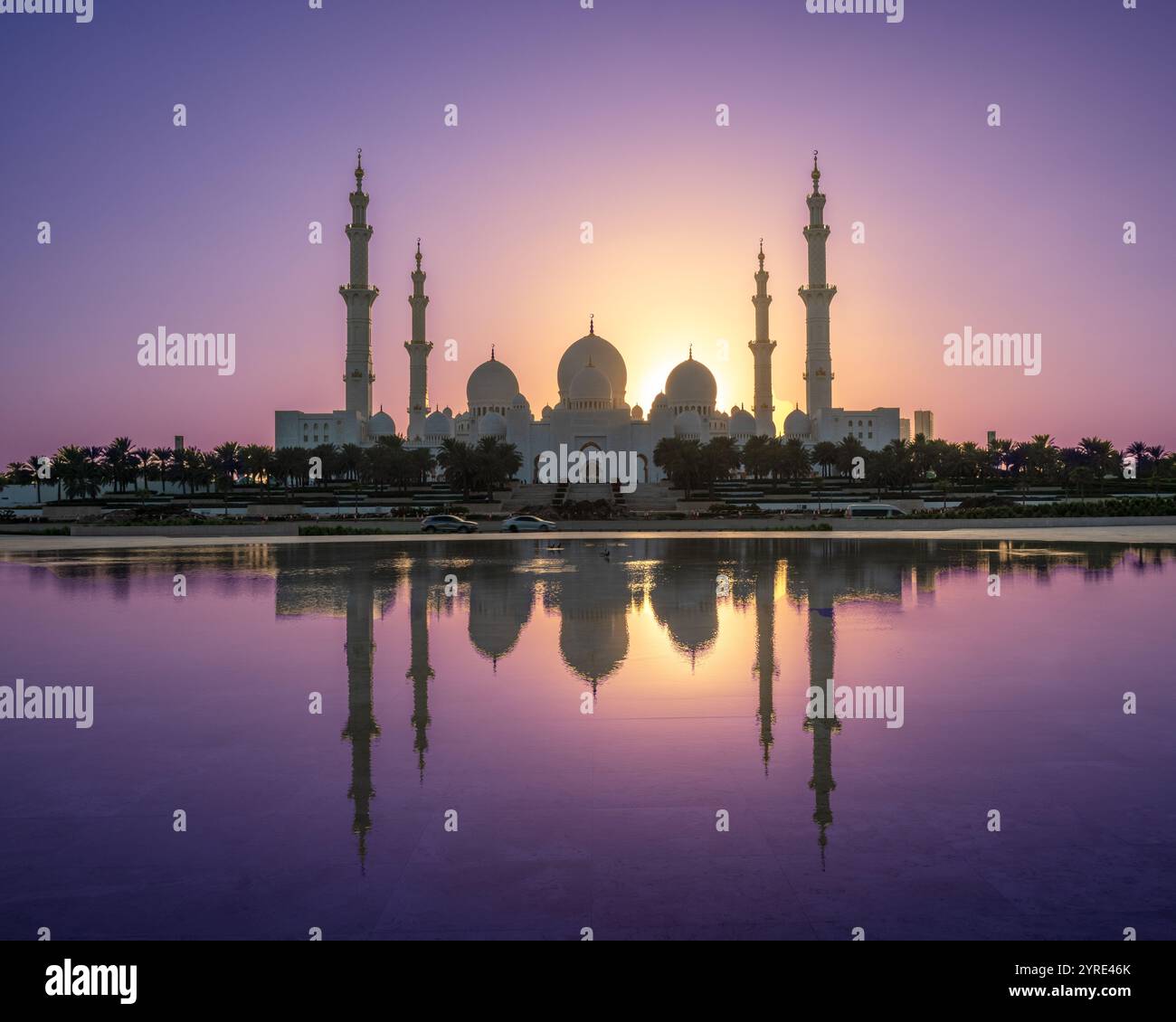 La grande Moschea dello Sceicco Zayed al tramonto con riflessi mozzafiato in acque tranquille e vivaci cieli viola e arancione, il simbolo di Abu Dhabi Foto Stock