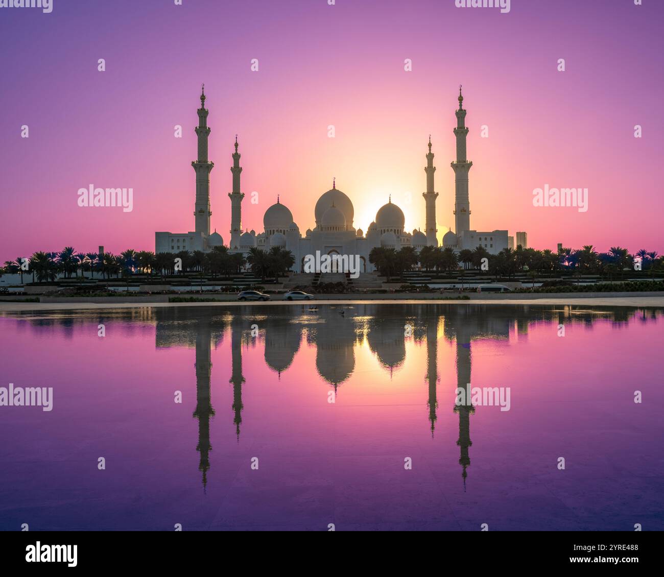 La grande Moschea dello Sceicco Zayed al tramonto con riflessi mozzafiato in acque tranquille e vivaci cieli viola e arancione, il simbolo di Abu Dhabi Foto Stock