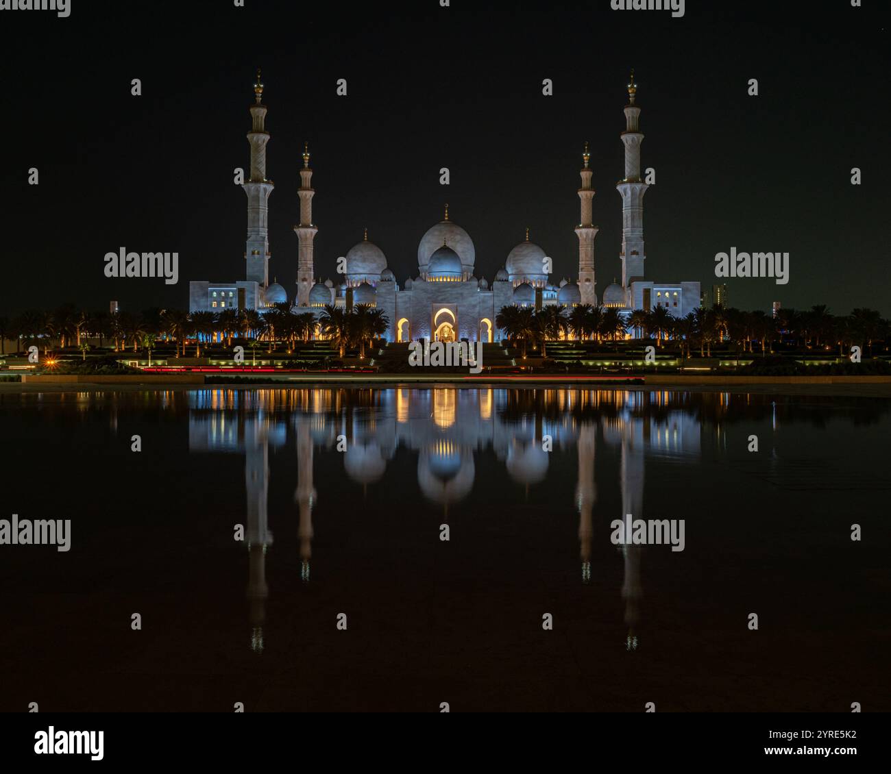 La grande Moschea dello Sceicco Zayed illuminata di notte, la sua splendida architettura si riflette in acque calme, rappresentando la grandezza culturale islamica Foto Stock
