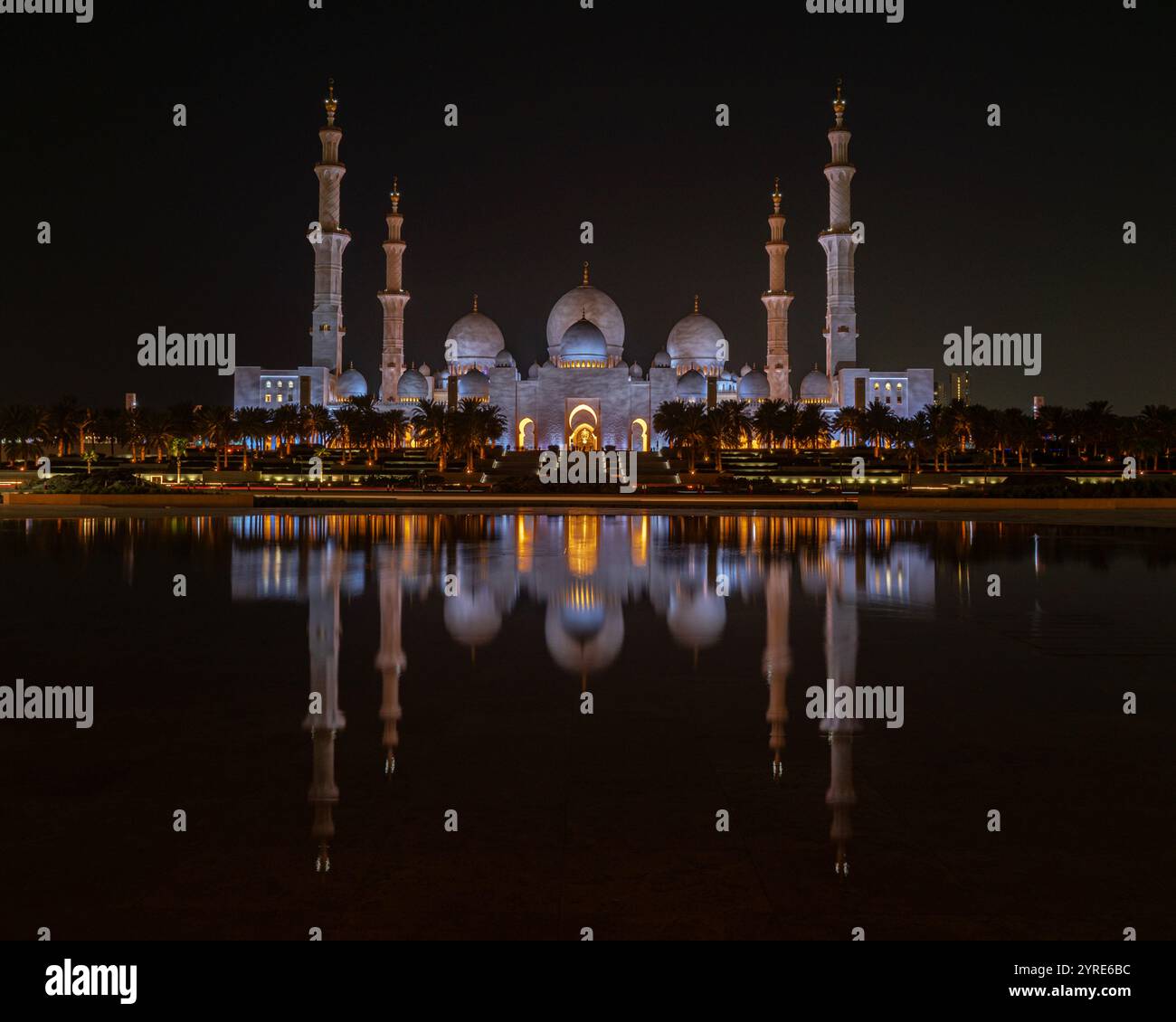 La grande Moschea dello Sceicco Zayed illuminata di notte, la sua splendida architettura si riflette in acque calme, rappresentando la grandezza culturale islamica Foto Stock