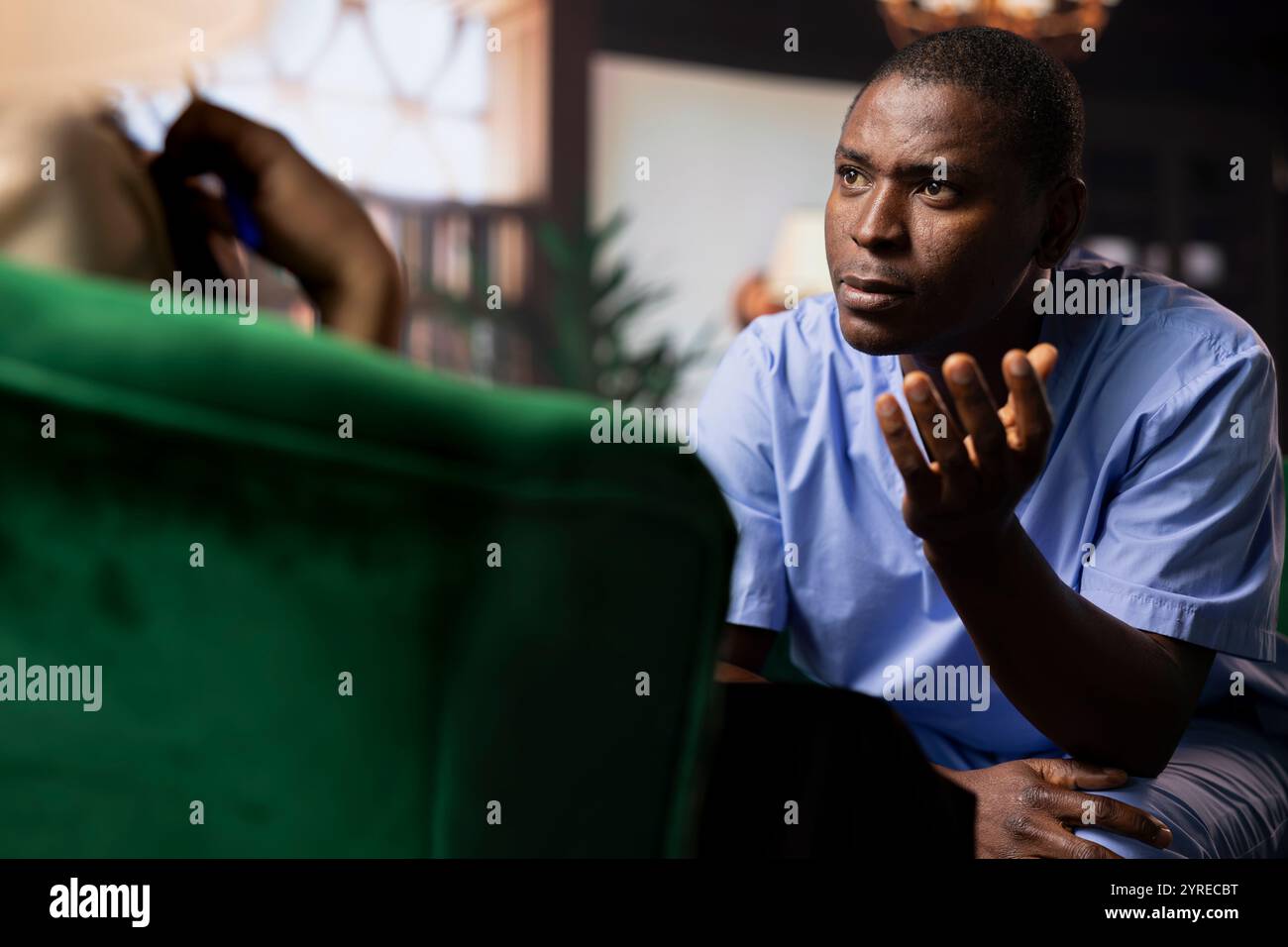 Infermiera afroamericana maschile che si apre in una sessione di consulenza, soffrendo di disturbo da stress post traumatico. Medico in terapia, lottando con l'impatto emotivo della perdita del paziente. Foto Stock