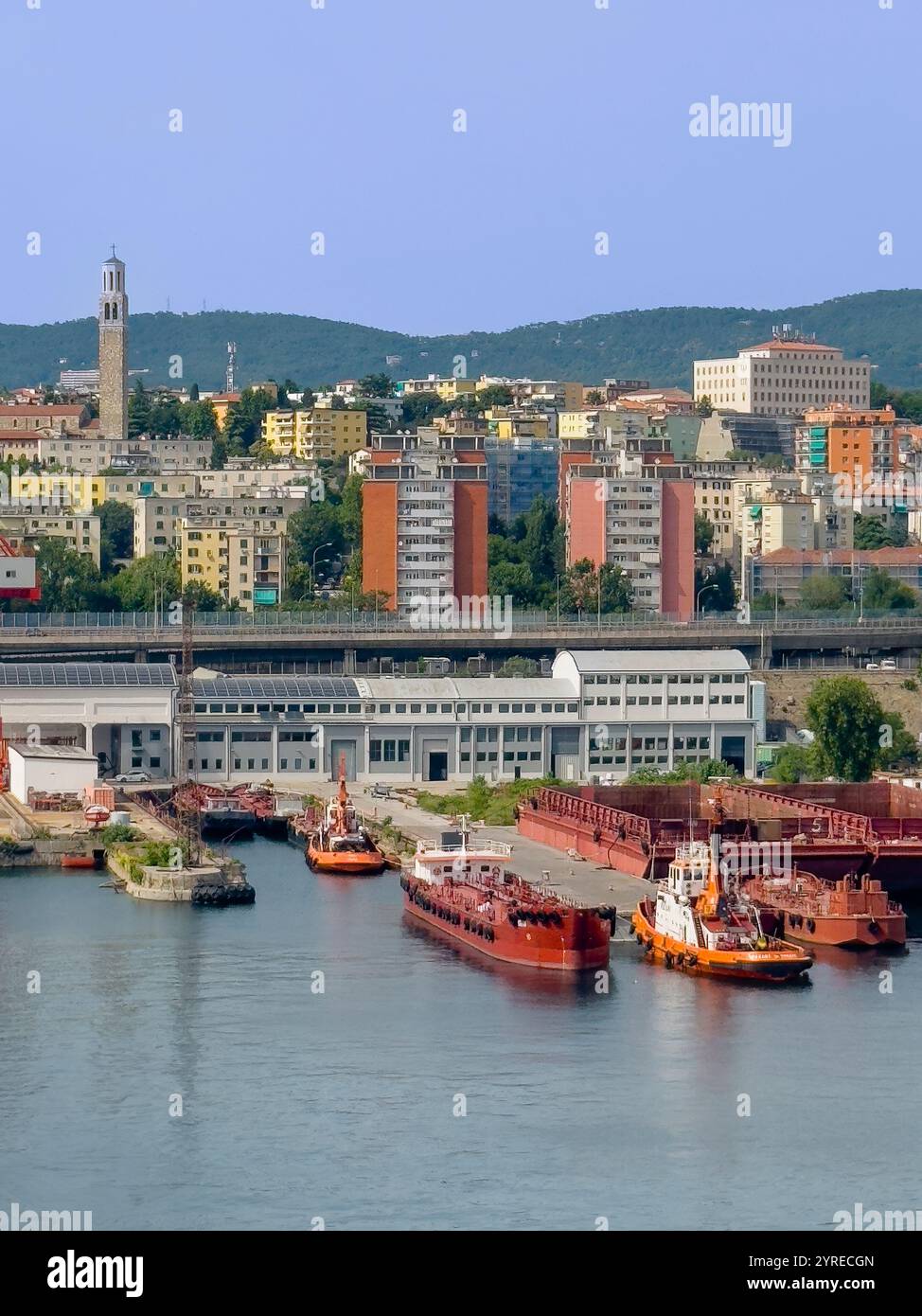 Trieste, Italia - 29 giugno 2024: Porto commerciale. Drydock, rimorchiatori e altre navi sulla banchina. Chiesa Cattolica parrocchiale della Madonna del Mare Foto Stock