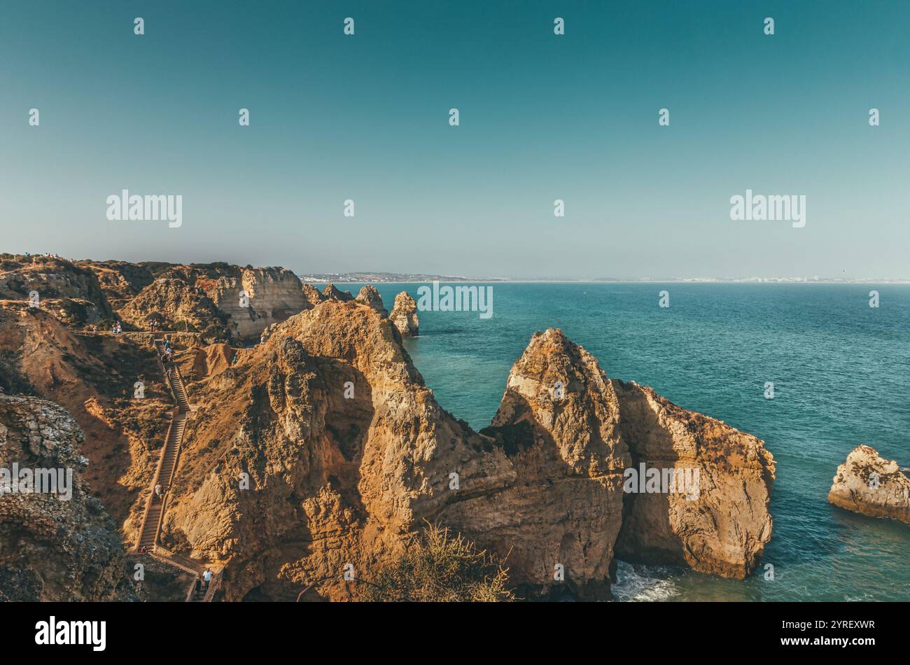 I turisti camminano lungo le scale di legno costruite sul lato di una scogliera a ponta da piedade, un punto panoramico a lagos, portogallo, con formazioni rocciose e t Foto Stock