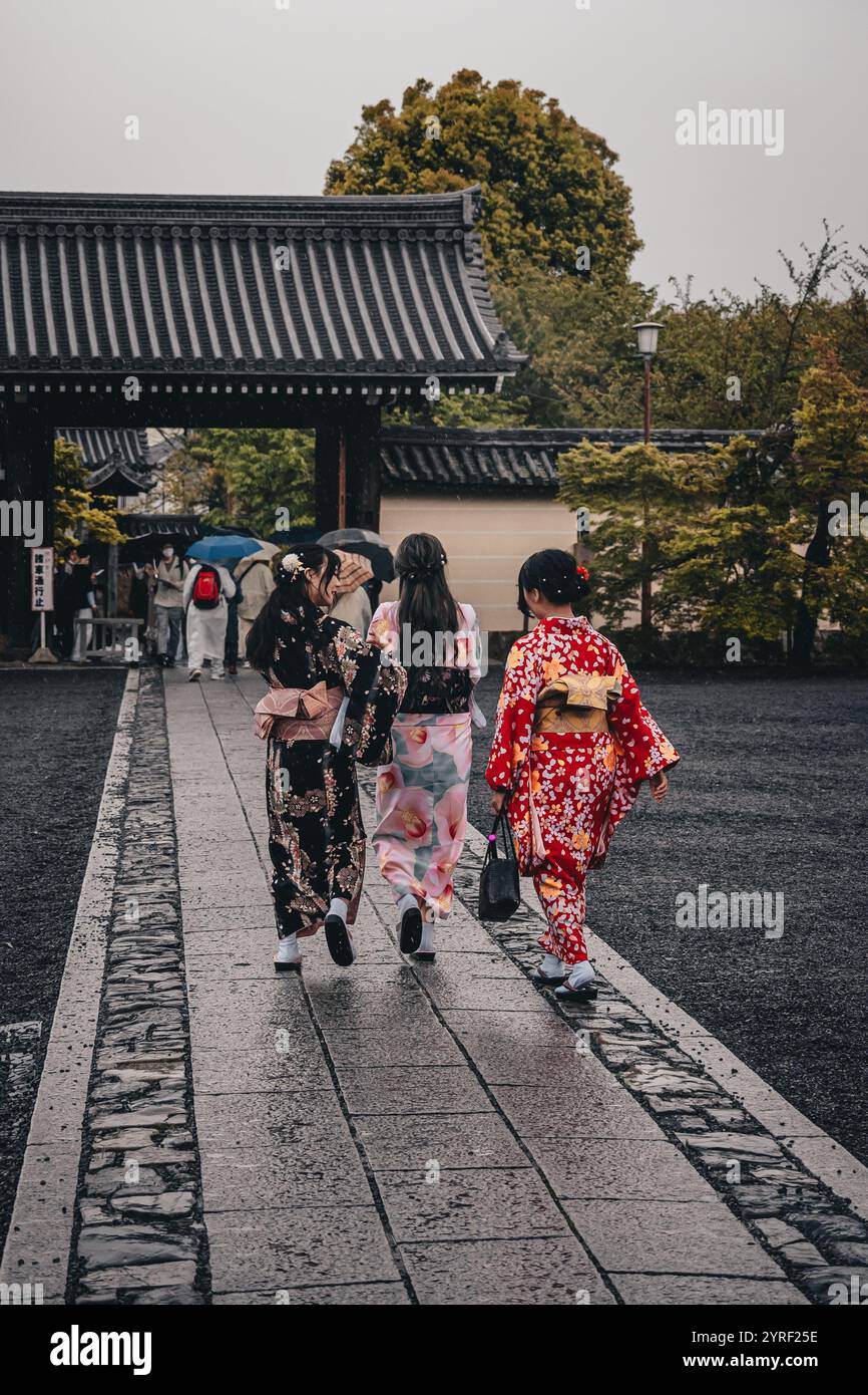 Le persone vestite con vivaci kimono tradizionali camminano graziosamente attraverso le strade storiche di Kyoto, in Giappone, circondate da fascino culturale. Foto Stock