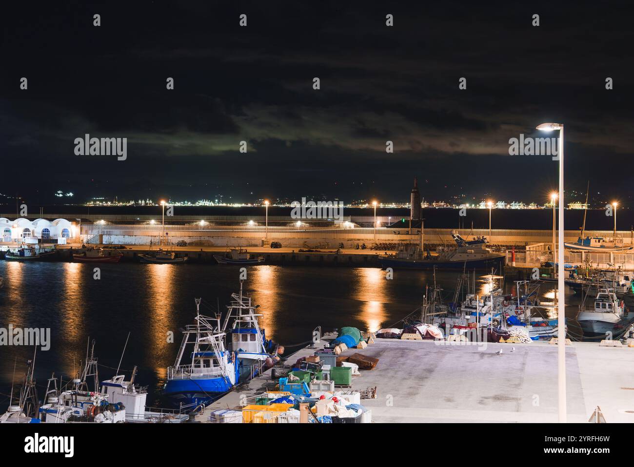 Vista notturna del porto di Tarifa, Spagna, con faro e barche Foto Stock