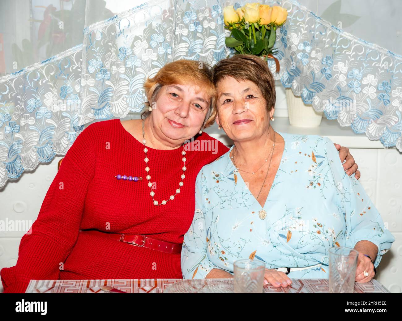 Due allegre donne russe, di 60 e 71 anni, sorridono e abbracciano a casa, celebrando la loro amicizia per tutta la vita. Un caldo momento di Unione, perfetto per te Foto Stock
