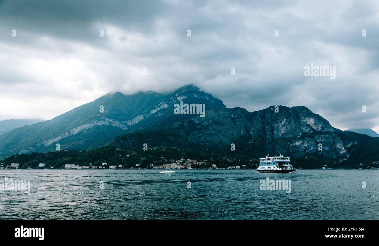 Il traghetto attraversa il lago di como con il cielo spettacolare e le montagne vicino a bellagio, in italia, offrendo paesaggi pittoreschi Foto Stock