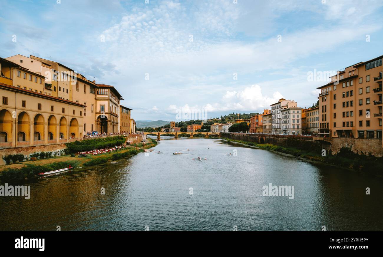 Gli atleti regnano sul fiume arno a firenze, con il ponte vecchio e la Galleria degli uffizi sullo sfondo che creano una scena pittoresca Foto Stock