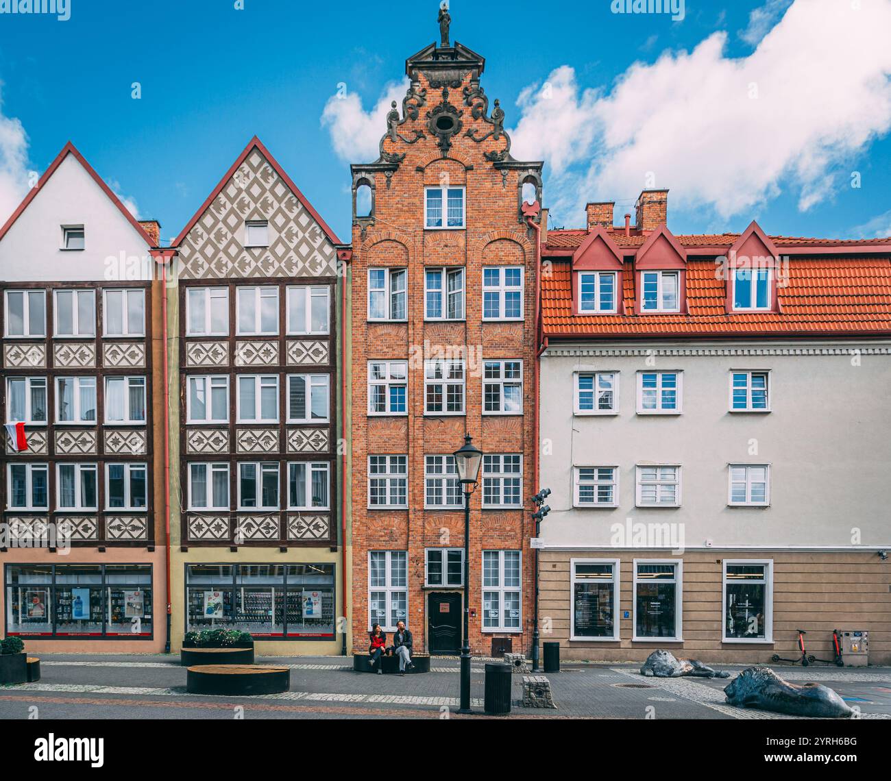 Due turisti riposano su una panchina di fronte a colorati edifici storici a danzica, in polonia, godendo della splendida architettura Foto Stock