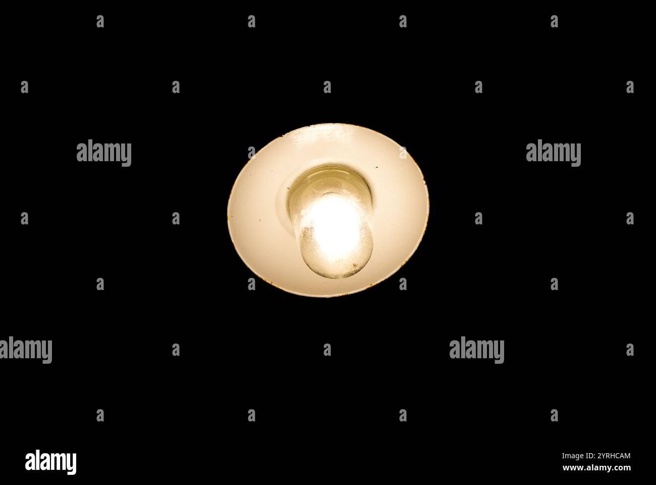 Luce al buio. La vecchia lampada si illumina leggermente su uno sfondo nero. Foto Stock