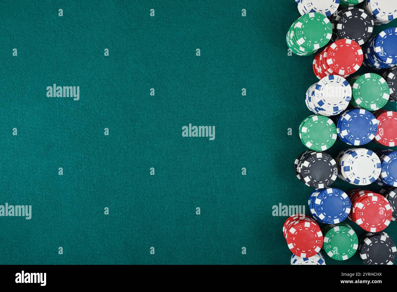 Dettaglio dello sfondo del casinò con pile di chip di scommesse di diversi colori a destra dell'immagine sul tappetino verde. Vista dall'alto. Foto Stock