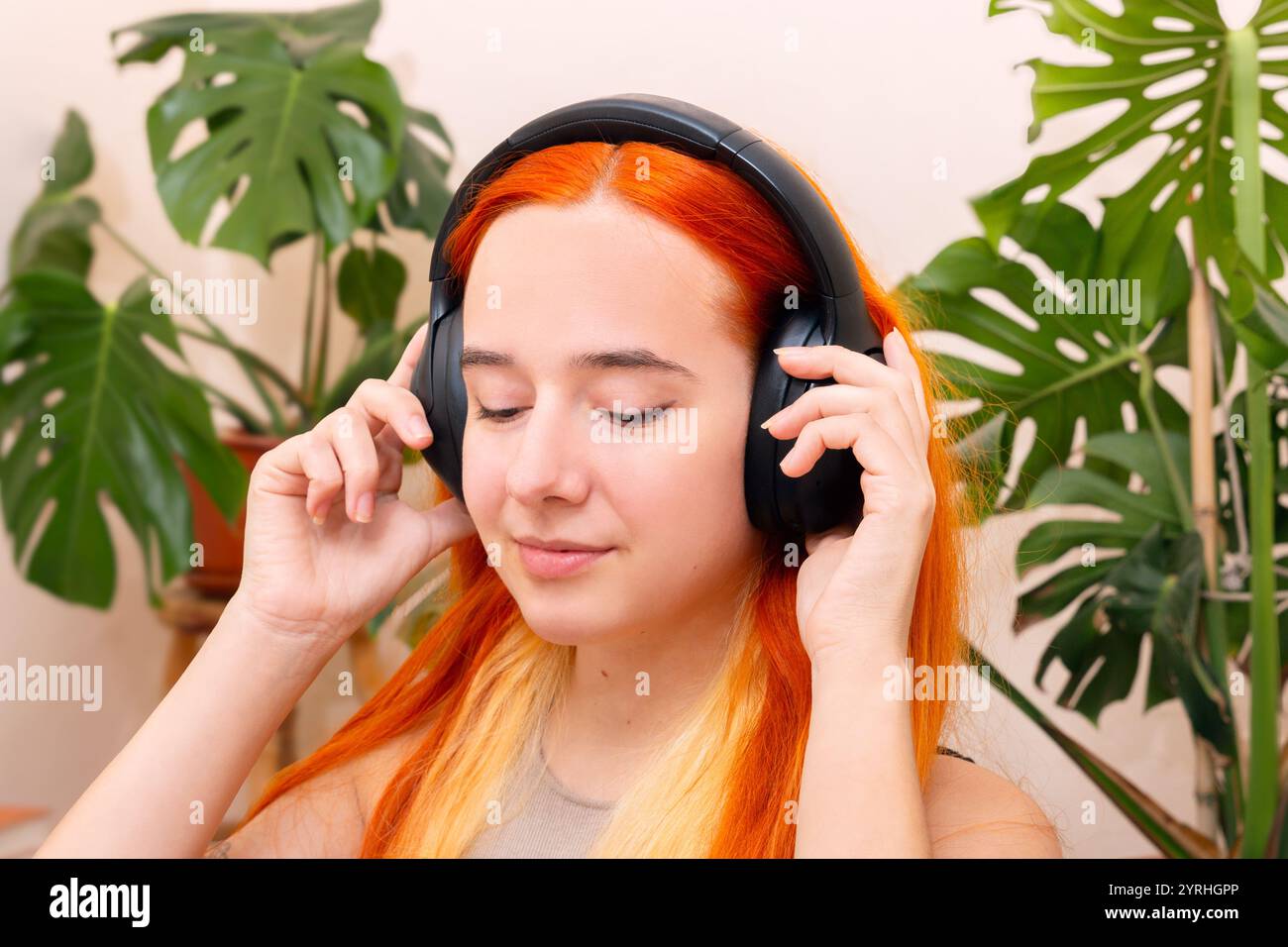 Una persona ama la musica attraverso le cuffie, immersa in un ambiente tranquillo circondato da lussureggianti piante verdi, incarnando uno stile di vita accogliente e sereno Foto Stock
