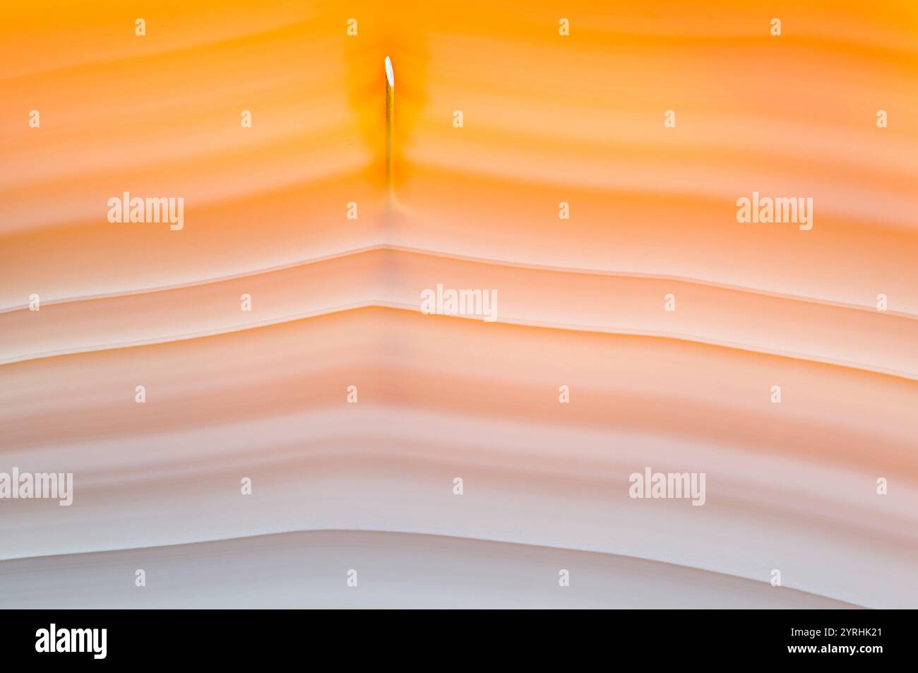 Un primo piano mozzafiato di agata brasiliana rivela strati arancioni e bianchi che scorrono. L'effetto retroilluminato mette in risalto la naturale translucenza della pietra, cre Foto Stock