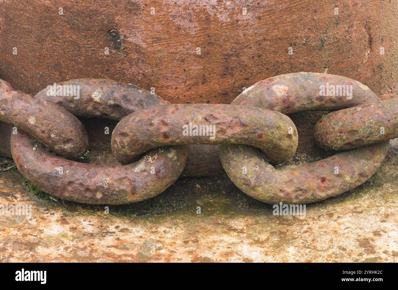 Un dettaglio ravvicinato di maglie a catena arrugginite, circondate da superfici metalliche invecchiate, che evocano un senso di decadenza industriale e storia in un deposito di rifiuti Foto Stock