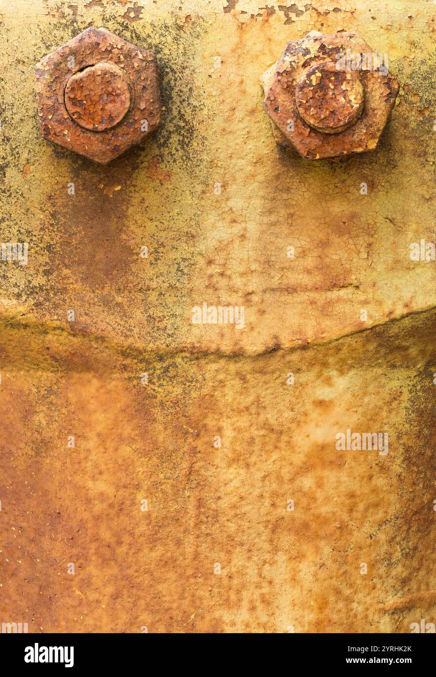 Un dettaglio ravvicinato di metallo arrugginito con due grandi bulloni corrosi, la texture e le tonalità calde evocano un'atmosfera industriale e rustica Foto Stock