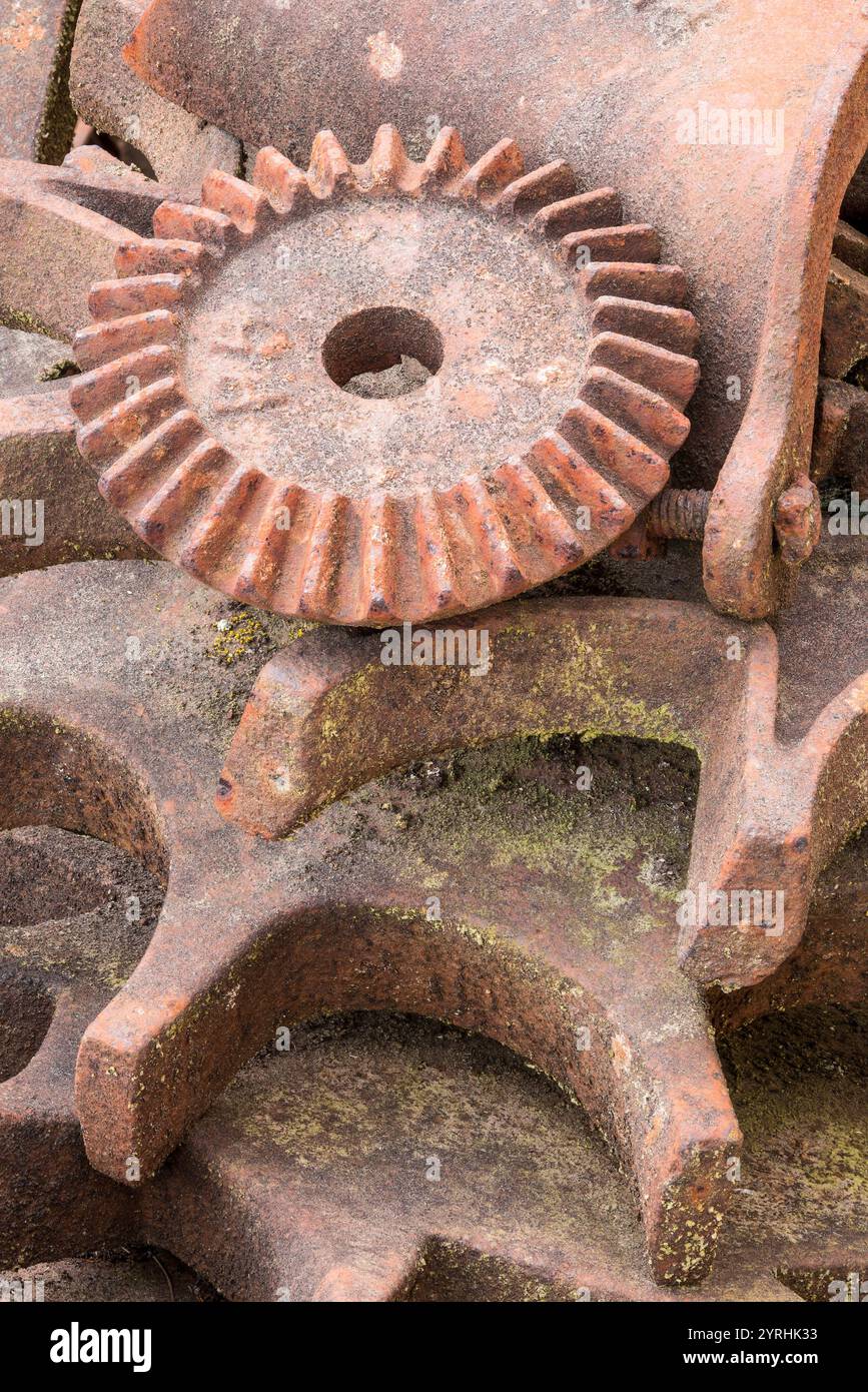 L'immagine dettagliata di ingranaggi arrugginiti e intemprati, che mostra le texture e la patina invecchiate, cattura l'essenza del decadimento industriale in un ambiente di deposito di rifiuti Foto Stock