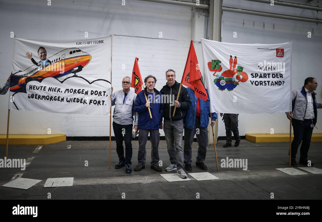 Wolfsburg, Germania. 4 dicembre 2024. I dipendenti della Volkswagen (VW) protestano con striscioni che recitano: "Qui oggi, là domani, via dopodomani" (l) e "quando salverà il Consiglio?" Durante una riunione di lavoro presso la sede centrale dell'azienda a Wolfsburg. La disputa sul lavoro alla Volkswagen, azienda automobilistica tedesca in crisi, sta arrivando a un'impennata a livello nazionale, con migliaia di posti di lavoro in gioco. Credito: Ronny Hartmann/AFP POOL/dpa/Alamy Live News Foto Stock