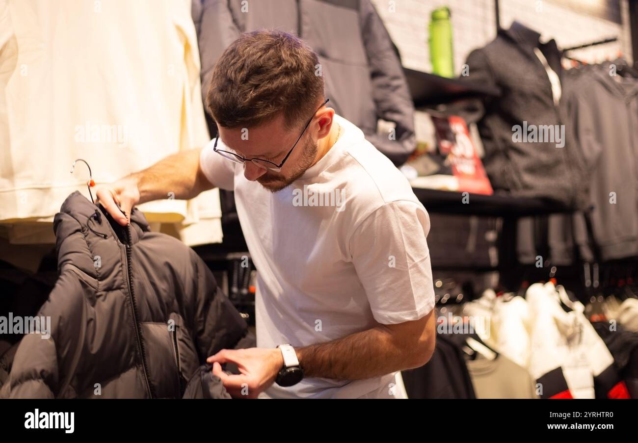 Un uomo guarda scarpe e vestiti in un negozio Foto Stock