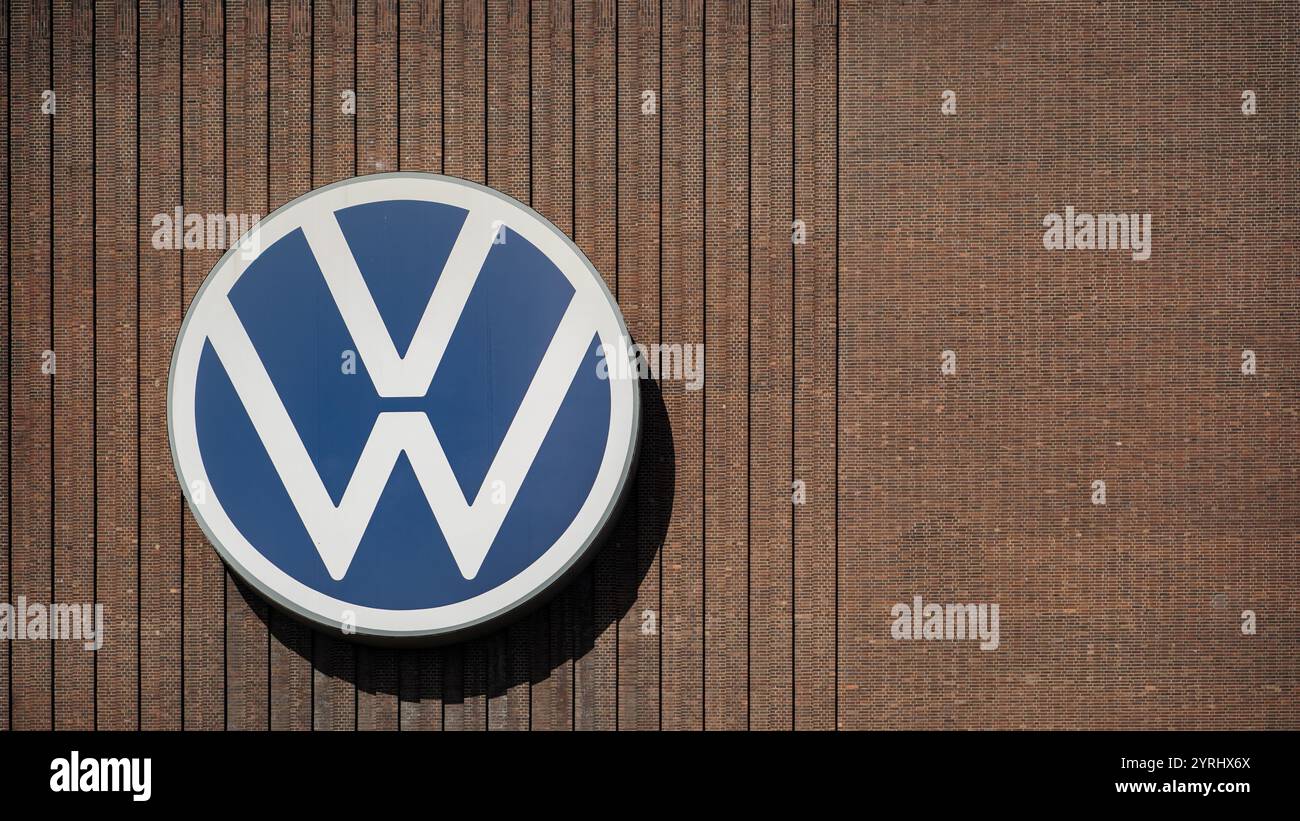Primo piano del grande logo Volkswagen sulla facciata della sede centrale Volkswagen a Wolfsburg in una giornata di sole Foto Stock