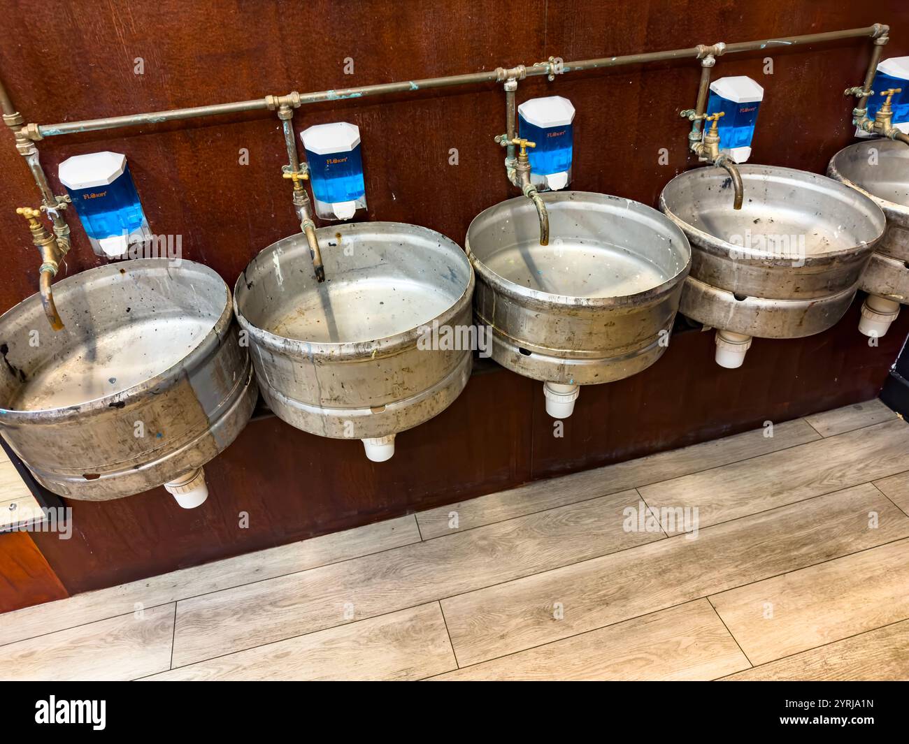 Fila di lavabi rustici in metallo rovesciato nei servizi igienici dispenser di sapone su parete di legno, realizzati in botti di birra, sede del teatro Alphabetti newcastle - Immagine stock catturata con smartphone